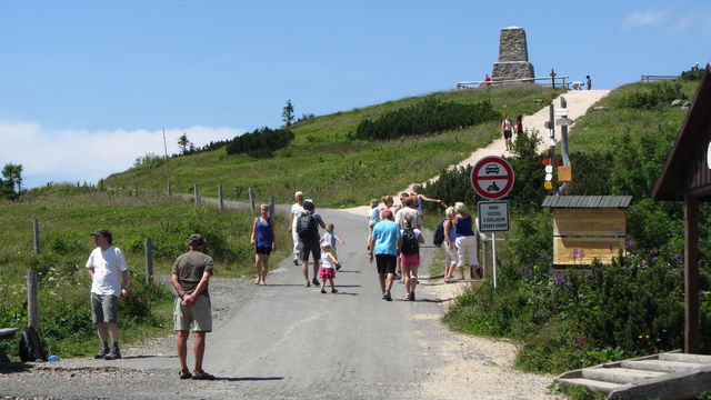 An der Vrbatova bouda führt die Asphaltstraße noch ein bißchen höher nach Westen . Der Wanderweg rechts am Denkmal vorbei fällt dahinter ab zur Elbfallbaude (Labská bouda).