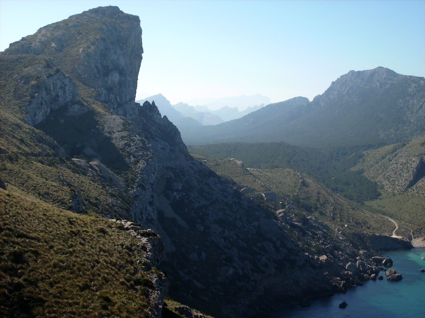 Panorama mit der Steilküste und den Gipfeln der Serra de Tramunta im Hintergrund.