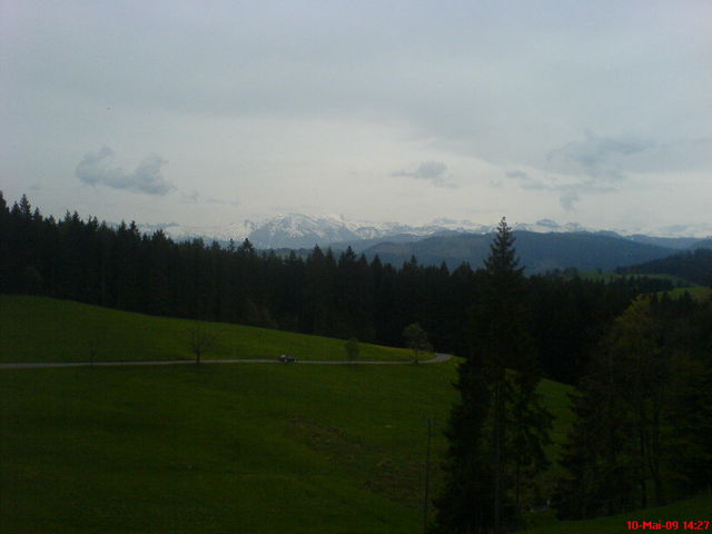 Bedecktes Wetter, und nur eine Handy-Optik, aber gut erkennbar rechts vom Tannenspitz der Drusberg (mit den zwei Felsstreifen)), hinter ihm ist der vieldiskutierte Pragelpass.