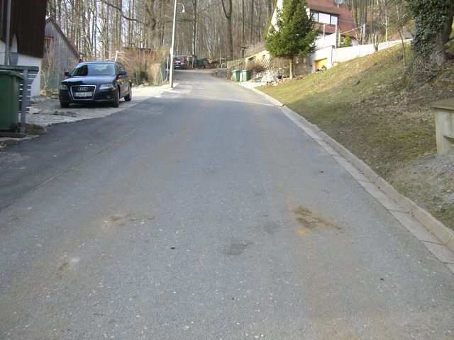 Am Berggasthof Glatzenstein rechts abgebogen befindet man sich auf dem Weg zum schwierigsten Teil des Anstieges. Vorne biegt die Straße rechts herum zum Ortsende und dem Wald.