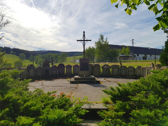 Grabsteine auf dem Friedhof von Dolní Paseky. Im Hintergrund eine Kolchose