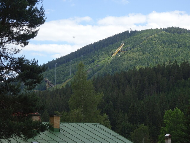 Die Schanzenanlage von Harrachov aus sicherer Distanz. Das Ende der Auffahrt ist allerdings schon auf Höhe des nach links aufsteigenden Fernsehturms links im Bild.